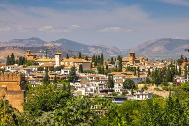 İspanya 'nın Granada kasabası. Parlak güneşli bir gökyüzünün altında dağlarda yuva yapmış resim gibi bir kasaba..