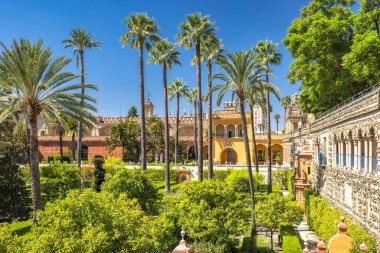 Sevilla 'nın Alcazar' ı, Sevilla kasabasındaki tarihi kraliyet sarayı, Endülüs, İspanya. Güneşli saray bahçeleri, palmiye ağaçları ve yemyeşil. Huzurlu bir vaha..