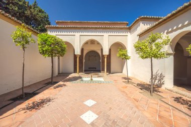 Alcazaba, Endülüs, İspanya, Avrupa 'daki Malaga şehrindeki saray ve kaleler. Çeşmeli ve kemerli sakin bir avlu. Güneş ışığı, huzurlu bir atmosfer yaratarak, huzur dolu bir alanı yıkıyor..