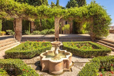 Alcazaba, Endülüs, İspanya, Avrupa 'daki Malaga şehrindeki saray ve kaleler. Çeşmeli, tuğladan kemerli, güneşli gökyüzünün altında yemyeşil bir bahçe..