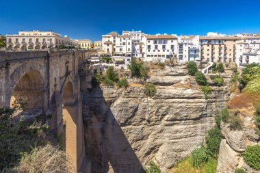 İspanya 'nın Ronda kasabasındaki El Tajo vadisindeki Puente Nuevo köprüsü. Derin bir vadiyi kaplayan antik taş köprü, beyaz binaların resimli olduğu bir kasabaya bakıyor..