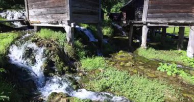 Bosna-Hersek 'in Jajce kasabası yakınlarındaki Pliva Nehri' ndeki Mlincici ahşap su değirmenleri. Su geleneksel değirmenlerin içinden akar, yemyeşil verimli ve tarihi bir manzara yaratır...