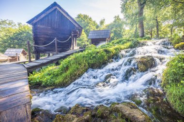 Bosna-Hersek 'in Jajce kasabası yakınlarındaki Pliva Nehri' ndeki Mlincici ahşap su değirmenleri. Şelale ve ahşap mimariyle yemyeşil bir alana kurulmuş kırsal su değirmeni köyü..