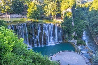 Bosna-Hersek 'in Jajce kasabasındaki Pliva Şelalesi, Avrupa. Idyllic şelaleleri verimli yeşilliklerle çevrili turkuaz bir havuza dökülüyor ve doğal güzelliklere huzurlu bir kaçış sunuyor..