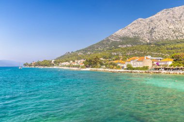 Hırvatistan, Avrupa 'daki Peljesac Yarımadası' nın deniz kıyısında. Güzel turkuaz sular huzurlu bir ortamda güneşli bir günde görkemli bir dağ sırasının altına kurulmuş büyüleyici bir sahil kasabasıyla tanışır..