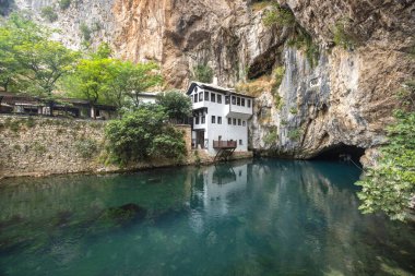 Bosna-Hersek 'in Mostar kenti yakınlarında Buna nehri olan Blagaj Tekke manastırı, Avrupa. Riverside House by Cliffside: Uçurumun kenarına kurulmuş sakin bir nehre bakan manzaralı bir ev.