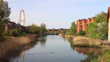 Gdansk, Kuzey Polonya, Avrupa 'nın Baltık kıyısında bir şehir. Berrak bir gökyüzü altında tuğla binalar ve doğal elementlerin yer aldığı nehir ve dönme dolabı olan sakin bir şehir. Huzurlu kentsel ortam.
