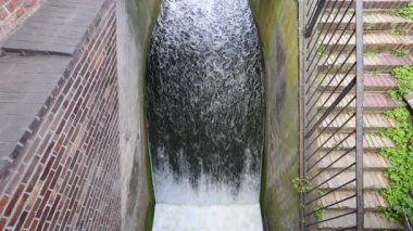 Şelale gibi akan su, beton bir kanaldan aşağı akarak göz hizasındaki bir perspektiften çekilen büyüleyici bir güç ve hareket görüntüsü yaratır..