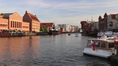 Gdansk, Polonya - 1 Mayıs 2025: Motlawa Nehri. Avrupa 'da gündüz vakti, tarihi binaların rıhtımda sıralandığı ve teknelerin denizde yüzdüğü görkemli nehir manzarası..