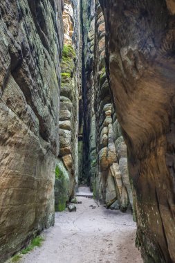 Adrspach-Teplice Rocks, sandstone formations in Hradec Kralove Region in Czech Republic, Europe. A narrow pathway cuts through towering rock formations, inviting exploration of this natural wonder.