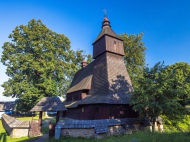 Church of Saint-Francis of Assisi in the village of Hervartov near Bardejov town in North-Eastern Slovakia, Europe. Rustic Wooden Church: A historical place of worship under a clear blue sky.