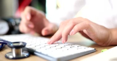 Dizüstü bilgisayarda çalışan ve klavyede yazan kadın doktor. Hastane masasında oturan hemşire terapisti.