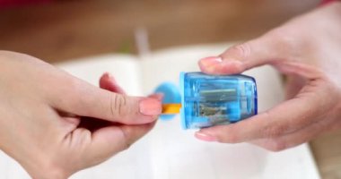 Kadın elleri, şeffaf mavi bileyicide kalem keskinleştiriyor. Kırtasiye konsepti