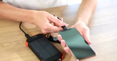 Güneş pillerindeki güç bankası USB kablosuyla akıllı telefonu şarj ediyor. Modern cihazlar ve yenilenebilir enerji kavramı