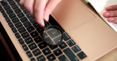 Dizüstü bilgisayar klavyesinin üzerinde büyüteç tutan kadın. İnternet kavramı hakkında bilgi ara
