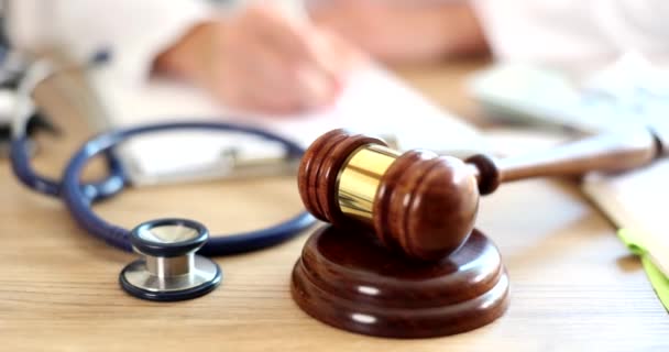 医者は法的な文書をテーブルで記入し ギャベルを判断します 医療犯罪の概念 — ストック動画