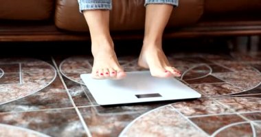 Tartının üzerindeki kadın bacakları ağırlığı yakından ölçer. - Evet. Diyet yapan kadın kilo kaybını kontrol ediyor