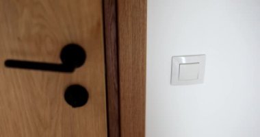 Evdeki rahat oturma odasının ışığını söndüren bir kadın. Enerji tasarrufu kavramı