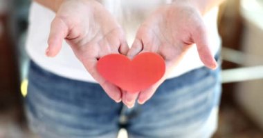 Sevgililer günü için kırmızı kağıt kalp tutan kadın eller. Yakın çekim 4K film yavaş çekim. Kan bağışı konsepti