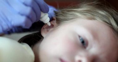 Çocuk kulaklarına iltihaplanma önleyici damlayan doktor. 4K 'lık filmi yavaş çekimde kapat. Çocuk konseptinde otitis medyasının tedavisi