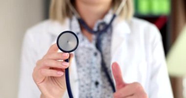 Doktor steteskop tutuyor ve başparmağıyla 4K 'lık filmi yavaş çekimde gösteriyor. Kaliteli sağlık sigortası kavramı 