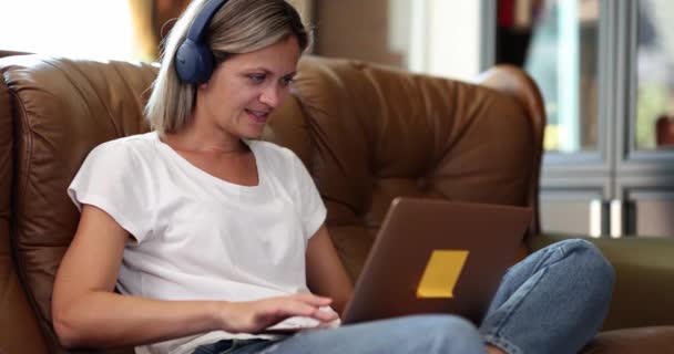 Schöne Frau Mit Kopfhörern Sitzt Auf Einem Sofa Wohnzimmer Und — Stockvideo