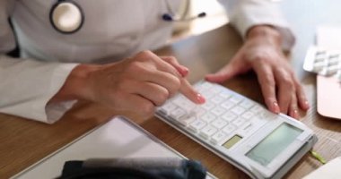 Kadın tıp doktoru ofis hastanesindeki ilaçların maliyetini hesaplamak için hesap makinesi kullanıyor. Sıhhiye klinikteki sağlık sigortasını hesapladı