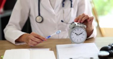 Diş fırçası ve çalar saati dişçi kliniğinde tutuyor. Diş bakımı ve ağız temizliği zamanlaması