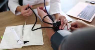 Kardiyolog, kan basıncını ölçmek için tonometre ve stetoskop kullanıyor. Hastanın sağlık durumu ve yüksek tansiyonu endişe verici.