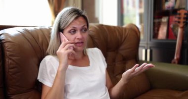 Telefon konuşmaları. Kendine güvenen genç bir kadın kanepede oturuyor ve telefonda konuşuyor. Cep telefonuna cevap veren ve arkadaşını ya da ortağını dinleyen bir kadın.