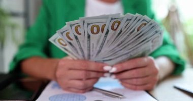 İş kadını işyerinde dolarları elinde tutuyor. Finansal başarı satış artışı ve karlı nakit yatırımı