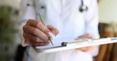 Tıbbi kayıtları dolduran pratisyen hekimler. Beyaz önlüklü doktor notlar yazar, evrakları hazırlar ve sigortaları doldurur.