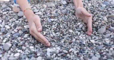 Kadın elleri kumsalda taş toplar. Plaj konseptinde rahatla ve sakinleş.