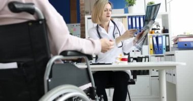 Tekerlekli sandalyedeki engelli, doktorla omurga röntgenini tartışıyor. Sırtından yaralandıktan sonra tıbbi rehabilitasyon