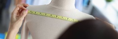 Moda tasarımcısı manken üzerindeki kıyafetlerin ölçüsünü alıyor. Atölye konseptinde terzilik