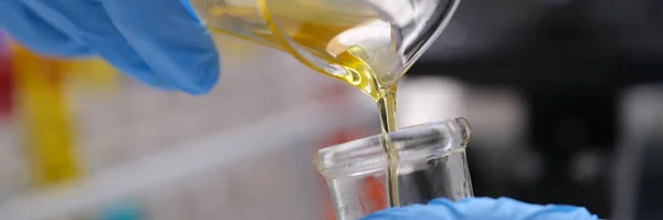 化学実験室での研究と液体油処理 化学試験管からガラスフラスコの概念に黄色の液体を手動で注ぐ科学者 — ストック写真