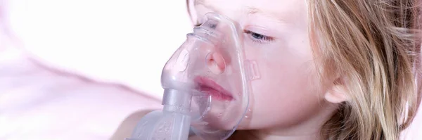 Sick little girl in medical oxygen mask using nebulizer. Long-term home oxygen therapy in children concept
