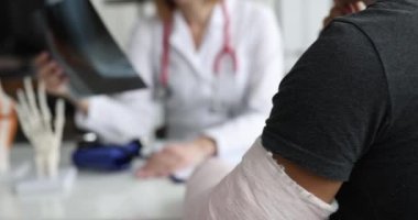 Doktor kırık kollu hastanın röntgenini inceliyor. Travmatolog ve kırık tedavisi konsepti