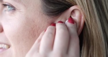 Kadın kablosuz bluetooth kulaklık takıyor ve düğmeye basıyor. Müzik konseptini dinlemek ve konuşmak için kulaklık.