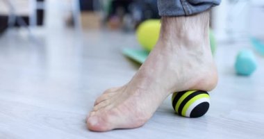Adam bacaklarına kramp giriyor ve topa masaj yapıyor. Sağlık terapisi ayak masajı konsepti.