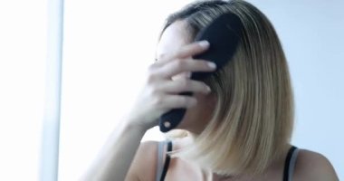 Kelliği olan korkmuş bir kız saçını yakından tarar. Saç bakımı ve tedavi konsepti