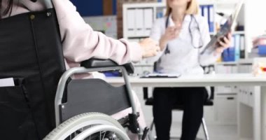 Doktor klinikteki tekerlekli sandalyedeki hastanın röntgenini inceliyor. Omurga yaralanması tedavisi ve rehabilitasyon konsepti