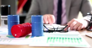 Oyuncak petrol varilleri iş adamlarının masasında dikiliyordu ve grafikler 4K 'lık yavaş çekim çekiyordu. Petrol ürünleri ticareti kavramı 