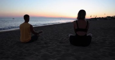 Çiftler gün batımında birlikte yoga ve meditasyon yapıyorlar. Aşk, ilişkiler ve rahatlama kavramı
