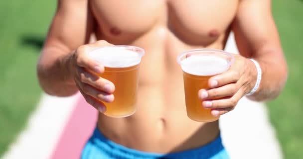 男子拿着两杯啤酒在海滩特写处 冰镇鲜美的莱托啤酒 — 图库视频影像