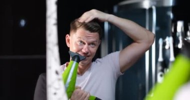 Genç yakışıklı adam aynaya bakar ve saç kurutma makinesiyle saç şekillendirir. Tarz sahibi erkek saç stilleri