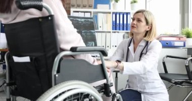 Kadın doktor, tekerlekli sandalyedeki bir hastayı röntgenle rahatlatır. Belkemiğinden yaralanan hastaların rehabilitasyonu