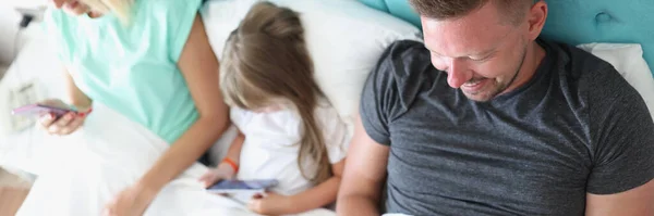 Pemandangan Keluarga Muda Dengan Anak Menggunakan Gadget Saat Berbaring Bersama — Stok Foto