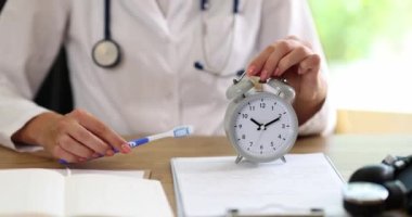 Elinde çalar saati ve diş fırçası olan bir doktor. Yakın plan. Ağız boşluğu için hijyenik prosedür, diş fırçalama.