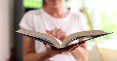 Kadın, kitabın sayfalarıyla ayakta duruyor, yakın plan. Okuma literatürü, kütüphane kavramını